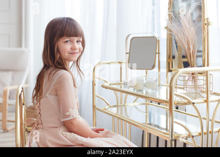 Cute little girl near oval mirror at dressing table Stock Photo