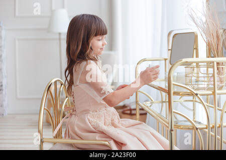 Cute little girl near oval mirror at dressing table Stock Photo