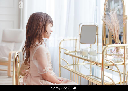 Cute little girl near oval mirror at dressing table Stock Photo