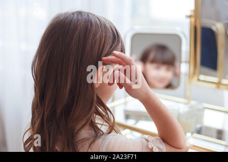 Cute little girl near oval mirror at dressing table Stock Photo