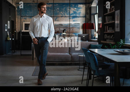 Full length of handsome young businessman in white shirt walking through the room in his own office. Stock Photo
