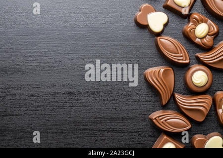 Various chocolate pralines on black table. Top view. Stock Photo
