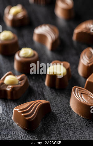 Various chocolate pralines on black table. Stock Photo