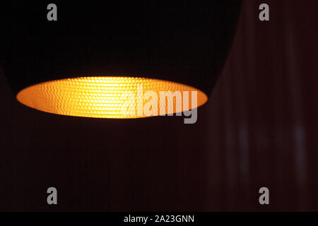 Close up of yellow light from a lamp shade in a dark room of a room, selective focus Stock Photo