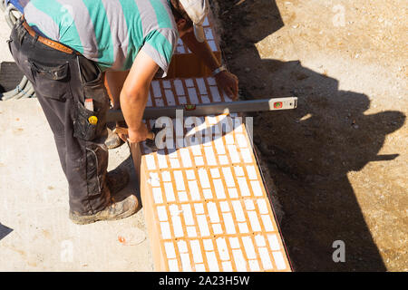 Two bricklayers are working on a construction site with a spirit level Stock Photo