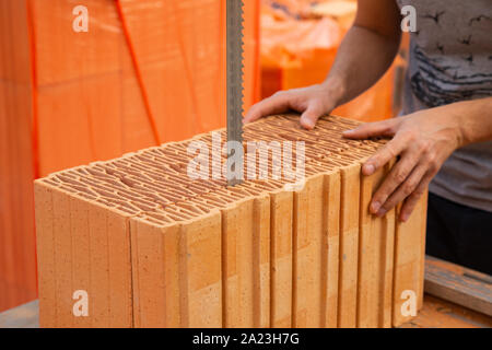 Bricklayer is cutting a brick with an electrical saw Stock Photo