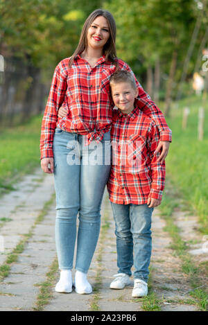 Beautiful mother and son are standing and hugging on a track in a park. Stock Photo
