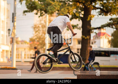 The guy performs a stunt on the BMX, jumping on the parapet. Stock Photo