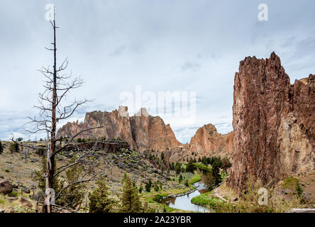 Smith Rock State Park establishing shot, landscape overview with Crooked River, Cathedral Rock, high cliffs clouds in sky. Stock Photo