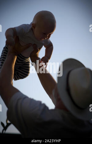 Young baby being held aloft by his father. Stock Photo