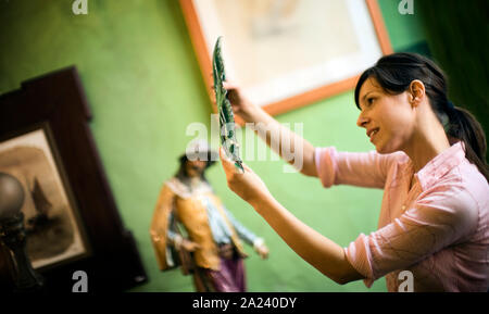 A woman thoughtfully looks at a decorative piece. Stock Photo