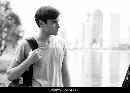 Young handsome man with backpack relaxing at the park Stock Photo