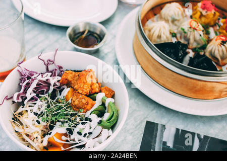 Pan-Asian food - vegetable salad bowl and different dim sums. Lunch for two with beer Stock Photo