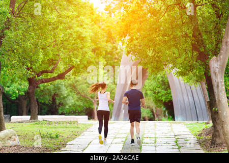 rear view young Couple jogging and running  in park Stock Photo