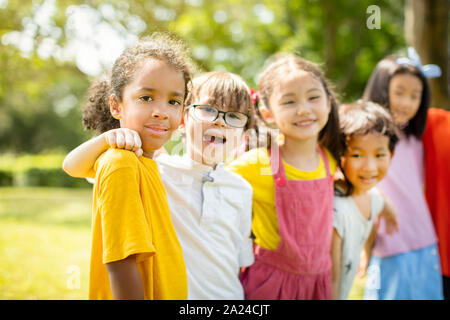 Multi-ethnic group of school children laughing and embracing Stock Photo