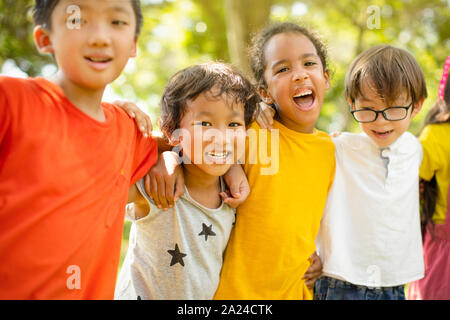 Multi-ethnic group of school children laughing and embracing Stock Photo