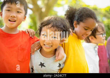 Multi-ethnic group of school children laughing and embracing Stock Photo