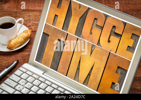 hygge time  word abstract in vintage letterpress wood type blocks on a laptop screen, Danish lifestyle concept Stock Photo