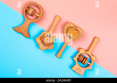 Minimalistic flat lay with a wooden rattle fish, bear,heart, star of beech  on an isolated multicolored vibrant geometric background. Toy for entertai Stock Photo