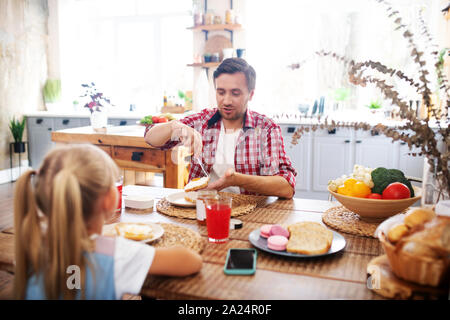 Father talking to his lovely girl while eating toasts for breakfast Stock Photo