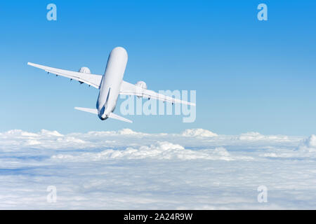 Airplane gains altitude flying into the distance above the clouds, rear view Stock Photo