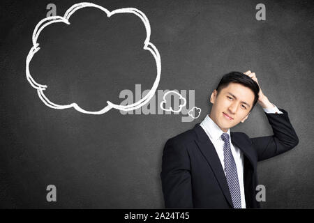 confused young businessman scratching his head with thinking bubble Stock Photo