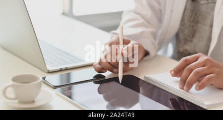 Cropped shot of young male freelancer writing on tablet while working on his project in his modern office room Stock Photo