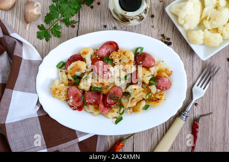 Warm salad of cauliflower, grilled sausages, green onions. A dish of cauliflower. Top view. Stock Photo