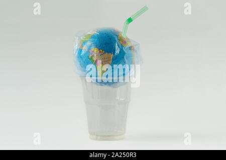 Earth globe in a plastic bag with straw over plastic glass - Concept of ecology and stop plastic pollution Stock Photo