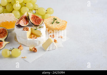 Brie or camembert cheese with figs, grapes, honey and nuts. Stock Photo