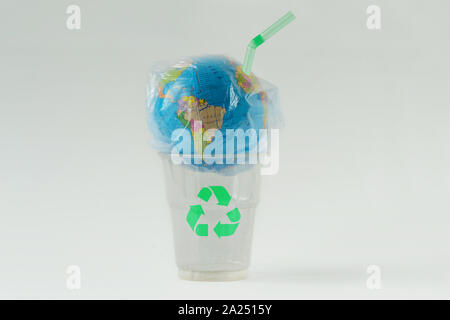 Earth globe in a plastic bag with straw on plastic glass with recycling symbol - Concept of ecology and stop plastic pollution Stock Photo