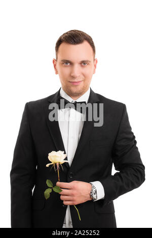 A portrait of a smiling handsome young man in a suit holding a flower, isolated on white background. Stock Photo