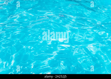 Light Blue swimming pool rippled water texture reflection. Beautiful blue water background with glare from the sun. Stock Photo