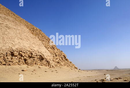 The Bent Pyramid is an ancient Egyptian pyramid located at the royal necropolis of Dahshur, approximately 40 kilometres south of Cairo, built under the Old Kingdom Pharaoh Sneferu (c. 2600 BC). A unique example of early pyramid development in Egypt, this was the second pyramid built by Sneferu. The Bent Pyramid rises from the desert at a 54-degree inclination, but the top section (above 47 meters) is built at the shallower angle of 43 degrees, lending the pyramid its very obvious 'bent' appearance. Stock Photo