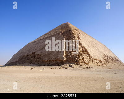 The Bent Pyramid is an ancient Egyptian pyramid located at the royal necropolis of Dahshur, approximately 40 kilometres south of Cairo, built under the Old Kingdom Pharaoh Sneferu (c. 2600 BC). A unique example of early pyramid development in Egypt, this was the second pyramid built by Sneferu. The Bent Pyramid rises from the desert at a 54-degree inclination, but the top section (above 47 meters) is built at the shallower angle of 43 degrees, lending the pyramid its very obvious 'bent' appearance. Stock Photo