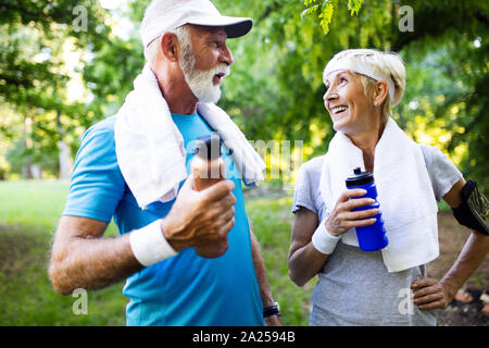 Beautiful senior couple running outside in forest Stock Photo