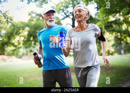 Beautiful senior couple running outside in forest Stock Photo