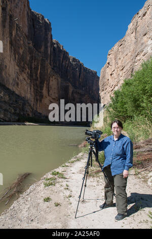 Photographer Carol M. Highsmith pauses between clicks of her Phase One 80-megapixel professional camera at the Santa Elena Canyon, deep in Big Bend National Park in Brewster County, Texas. A sheer rock wall in Mexico is to the left, one in the United States to the right Stock Photo
