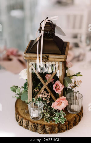 Wooden lantern filled with moss stands, white and pink flowers, small candlestick Stock Photo
