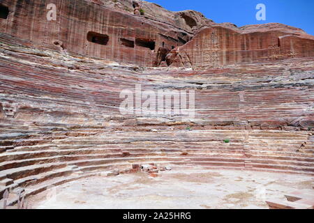 first century AD Nabatean theatre in Petra, Jordan. Substantial part of the theatre was carved out of solid rock, while the scaena and exterior wall were constructed. The theatre's auditorium consists of three horizontal sections of seats separated by passageways and seven stairways to ascend. The theatre could accommodate a number of approximately 8500 people. The theatre was built in the cultural and political apex of the Nabatean kingdom under Aretas IV (9 BC-40 AD), In 1812, the city of Petra and Al-Khazneh was rediscovered by Swiss explorer Johann Ludwig Burckhardt Stock Photo