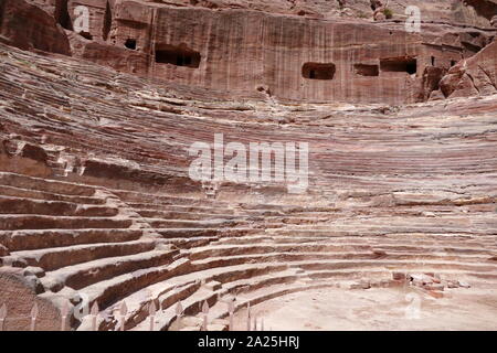 first century AD Nabatean theatre in Petra, Jordan. Substantial part of the theatre was carved out of solid rock, while the scaena and exterior wall were constructed. The theatre's auditorium consists of three horizontal sections of seats separated by passageways and seven stairways to ascend. The theatre could accommodate a number of approximately 8500 people. The theatre was built in the cultural and political apex of the Nabatean kingdom under Aretas IV (9 BC-40 AD), In 1812, the city of Petra and Al-Khazneh was rediscovered by Swiss explorer Johann Ludwig Burckhardt Stock Photo