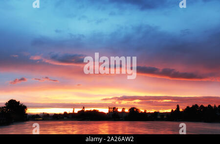 fantastic landscape. The dramatic scene sunset over a lake, rays erupt through the heavy storm clouds reflected in the water. color in nature. Stock Photo