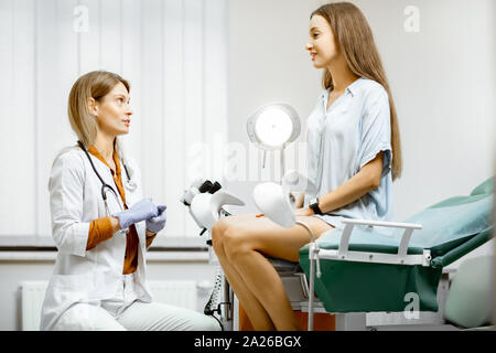 Gynecologist preparing for an examination procedure for a pregnant woman sitting on a gynecological chair in the office Stock Photo