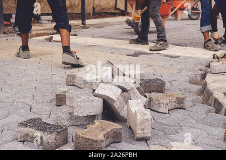 Construction workers installing and arranging precast concrete pavers stone for road at the construction site. Stock Photo
