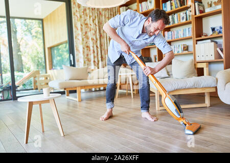 Hausmann cleans parquet floor in the living room with the vacuum cleaner Stock Photo