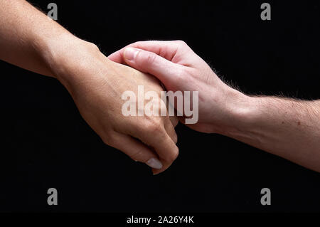 Male and female hands together showing emotions on black background Stock Photo