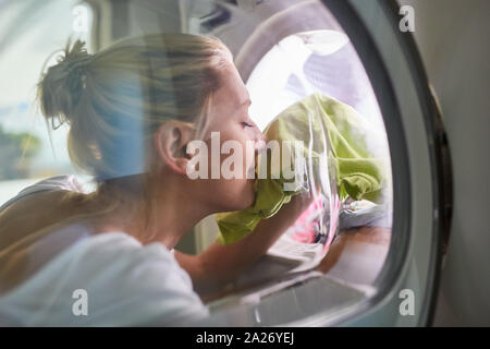 Housewife smells of clean laundry fresh from washing machine or dryer Stock Photo