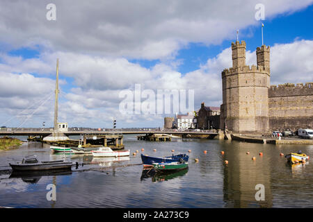 View of swing bridge across Afon Seiont River to Edward 1st 13th century castle at high tide with moored boats. Caernarfon Gwynedd Wales UK Britain Stock Photo