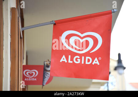 White logo of 'Algida' on a red flag, with a Cornetto icecream on the background, out of focus. Algida is an icecream brand owned by Unilever Company. Stock Photo