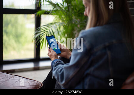 Woman sitting on the couch and trying a new VPN app for privacy Stock Photo